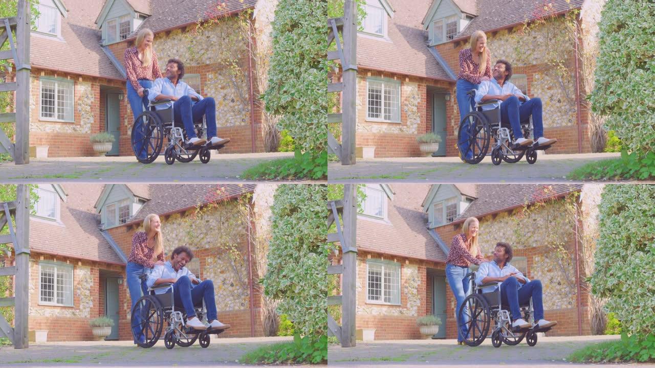 微笑的成熟夫妇与坐在轮椅上的男人被女人推到家外