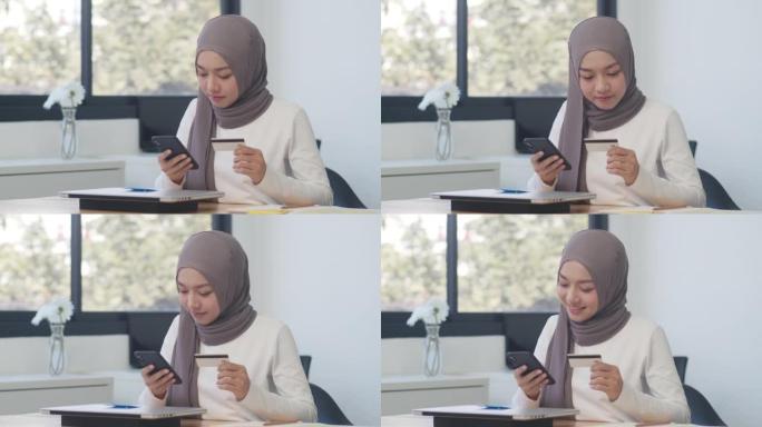 亚洲穆斯林女士使用电话，信用卡在办公室购买和购买电子商务互联网。
