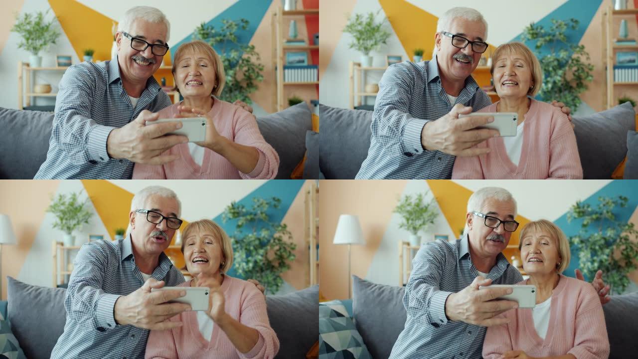 退休人员男子和女士在家中挥舞着智能手机进行在线视频通话