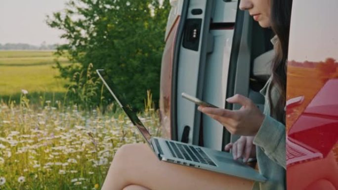 DL女人在停在乡下的露营车中使用智能手机和笔记本电脑