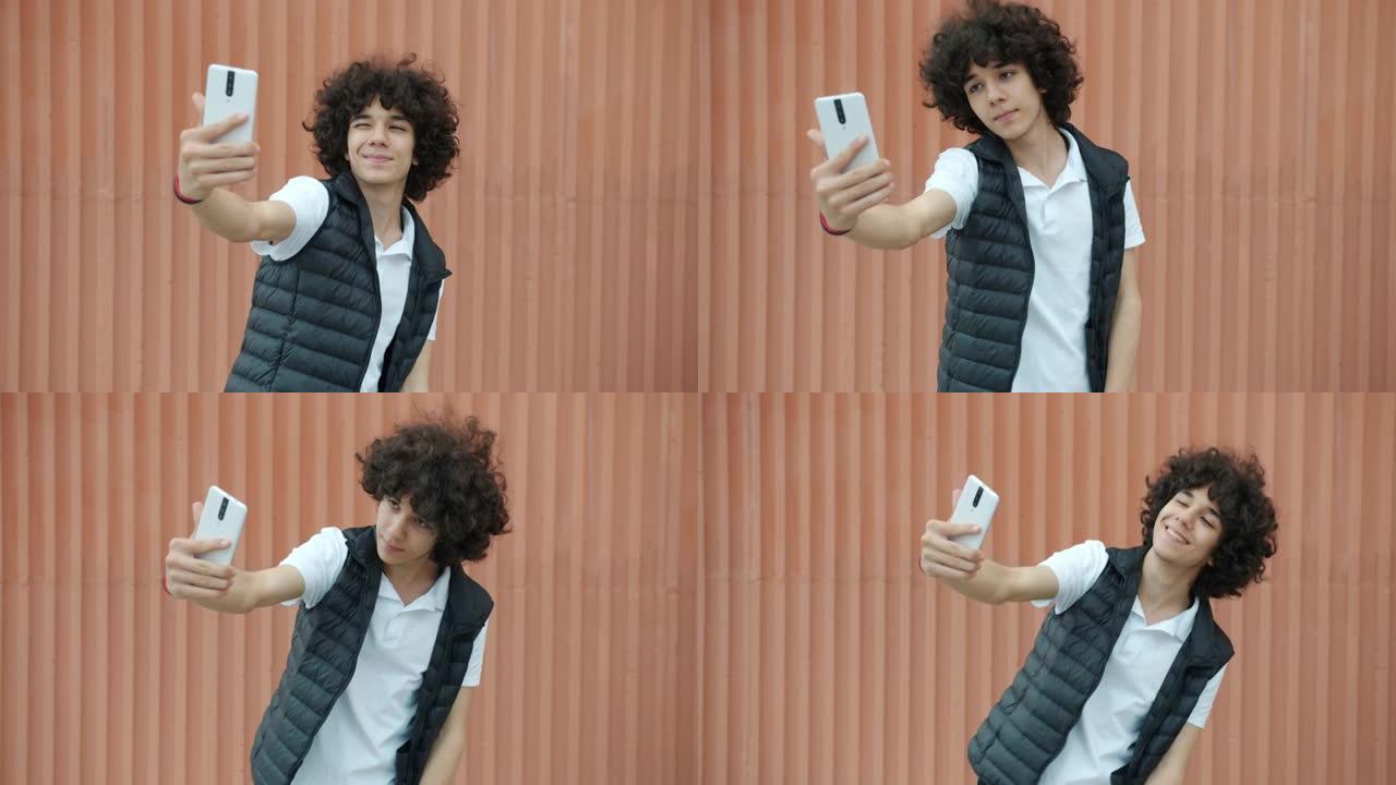 好看的中东少年在户外自拍，为智能手机相机摆姿势