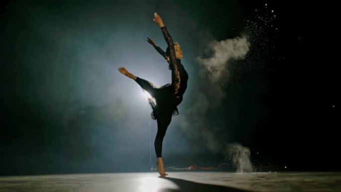 超级SLO MO职业芭蕾舞演员在舞台上旋转时向空气中扔灰尘