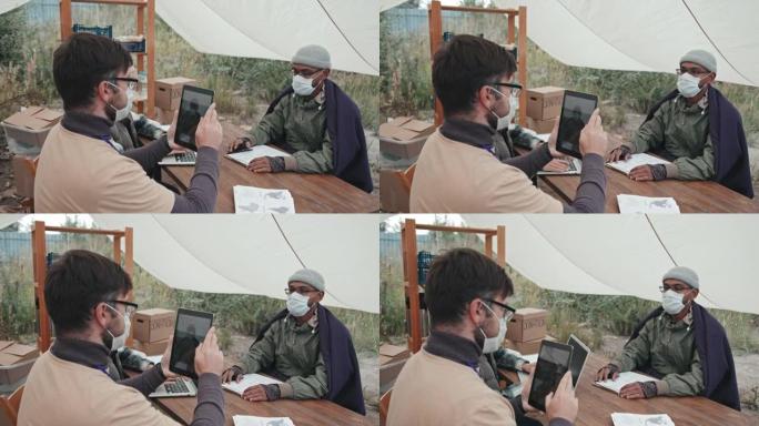 社会工作者为戴着口罩的难民男子拍照