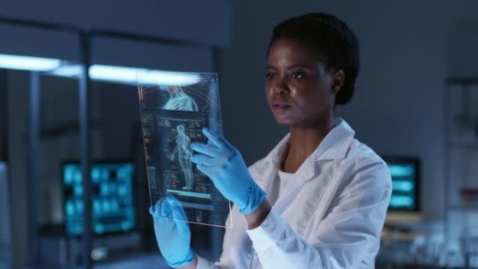 美丽的年轻非洲裔美国科学家，穿着实验室外套，戴着防护手套，在现代实验室的HUD上工作。具有深蓝色配色