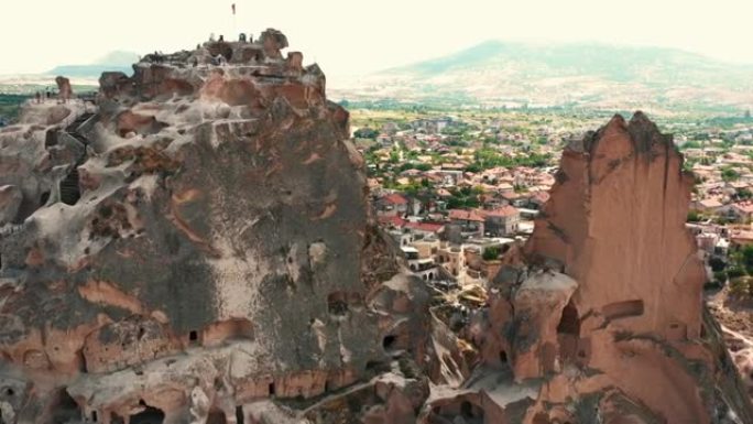 无人机在落基山内令人惊叹的古老历史定居点附近飞向土耳其卡帕多西亚的小镇。