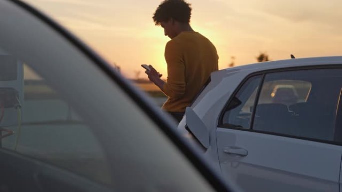 非洲男子在停车场靠在汽车上时使用手机
