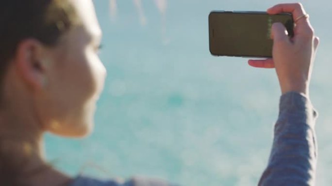 女人，海滩和电话日落摄影旅行或夏季冒险记忆。智能手机、内容创建和博客影响者通过海洋户外移动应用在假期