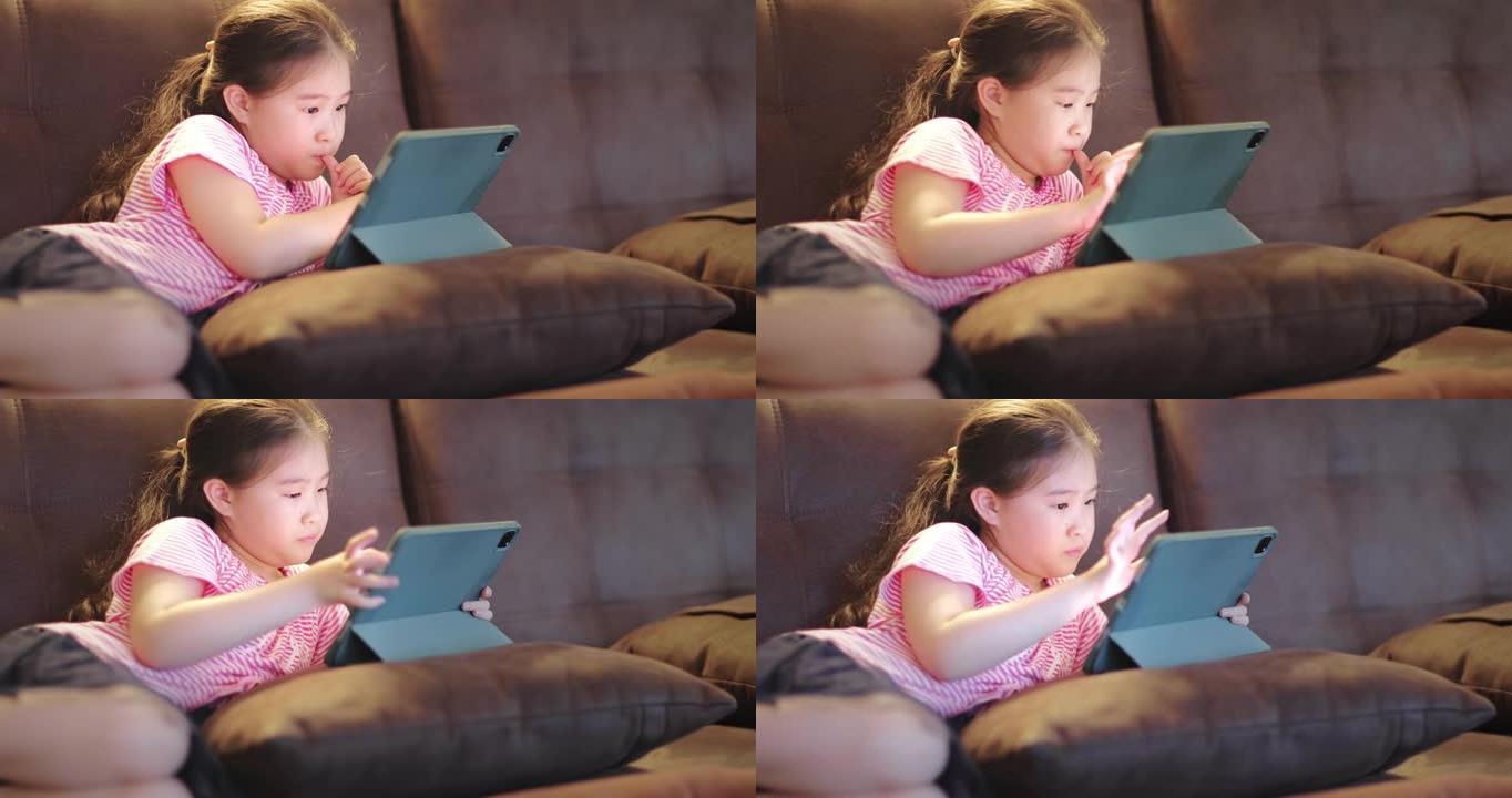 快乐可爱的女孩在沙发上使用数字平板电脑