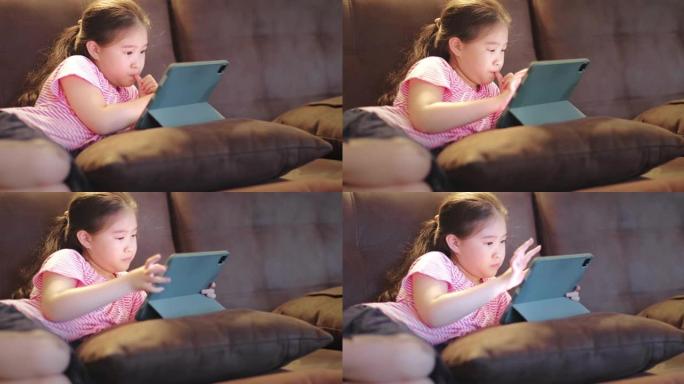 快乐可爱的女孩在沙发上使用数字平板电脑