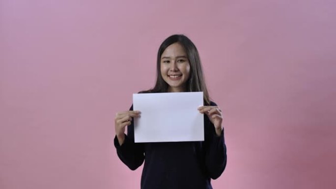 美丽的亚洲女人在粉红色背景下的工作室里展示纸张