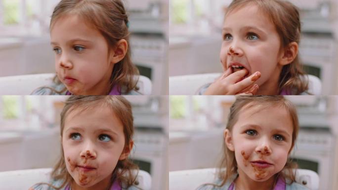女孩在快乐的脸上吃巧克力，双手凌乱，周末早上坐在厨房里。甜食，糖果和有趣的甜点的孩子，巧克力棒或饼干