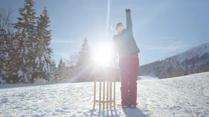 肖像: 开朗的女游客站在雪橇旁边时伸出手臂