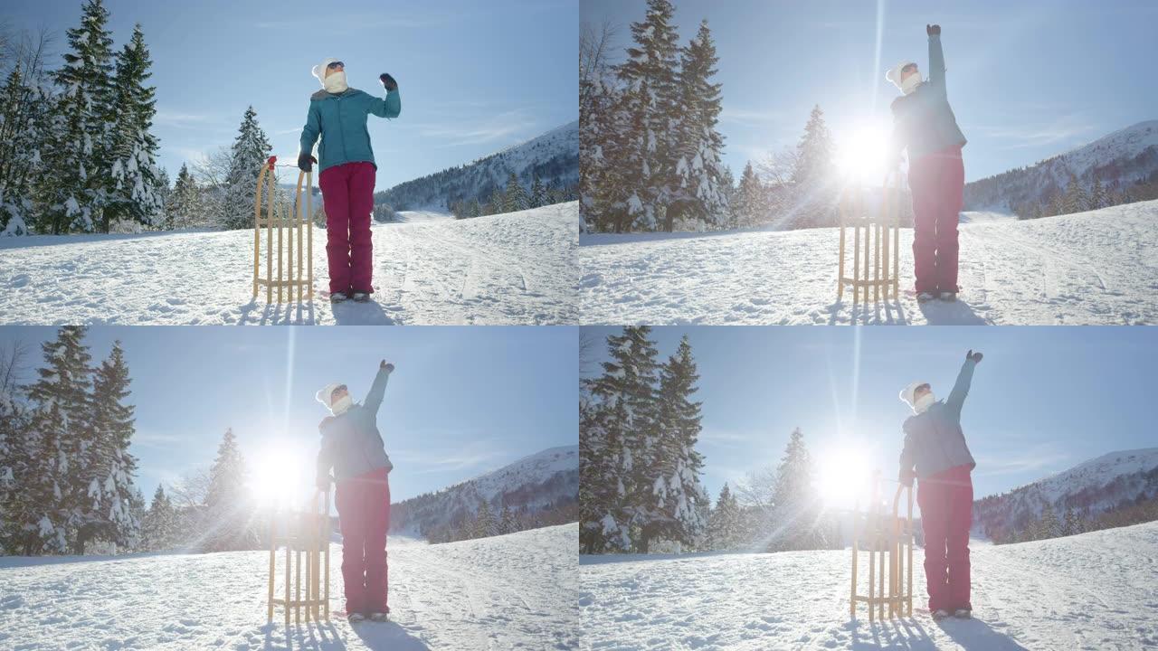 肖像: 开朗的女游客站在雪橇旁边时伸出手臂