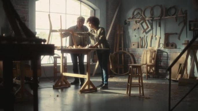 一家家具车间的小企业主讨论了新的木制餐桌椅的设计。中年木匠和一个在家具网上商店工作的年轻女学徒。