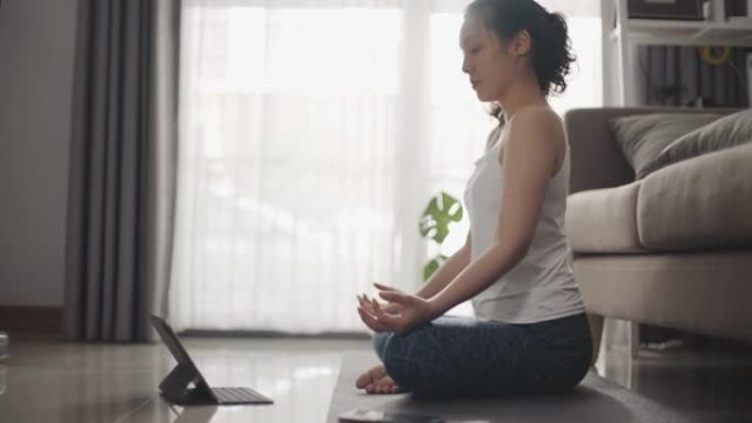 亚洲运动女子在家做在线瑜伽课