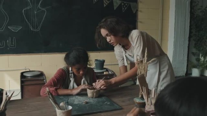 女人帮助女孩雕刻粘土