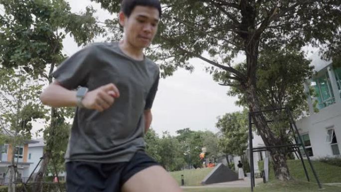 一个手臂残疾的人在公园草坪上踢足球。