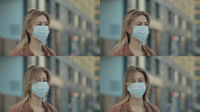 现代休闲年轻一名妇女戴着防护医用口罩并站立的特写肖像。安全的概念和睁开眼睛的人在检疫的社会距离。城市