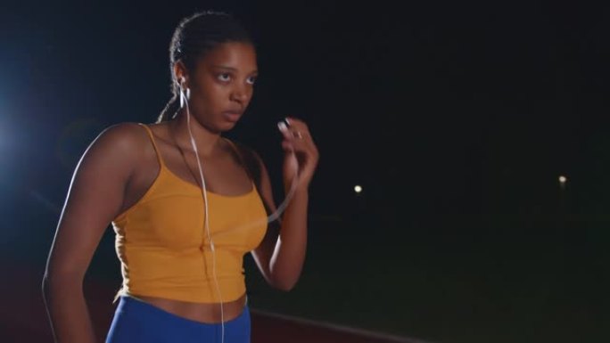 SLO MO非洲裔美国运动员在准备在跑道上训练时放置入耳式耳机