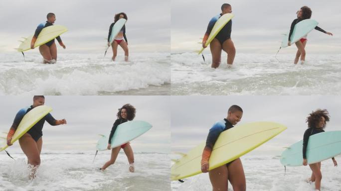 快乐的非洲裔美国女性朋友抱着冲浪板跑出大海