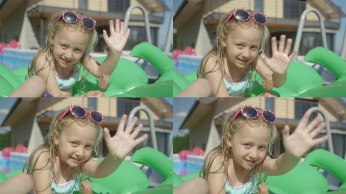 特写: 可爱的小女孩，在游泳池里放着冰淇淋吧，向相机挥手