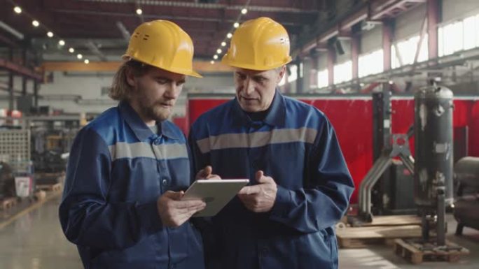 用平板电脑在工作场所交谈的男性工厂工人