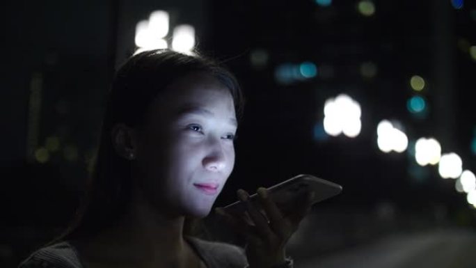 年轻的亚洲妇女晚上使用手机