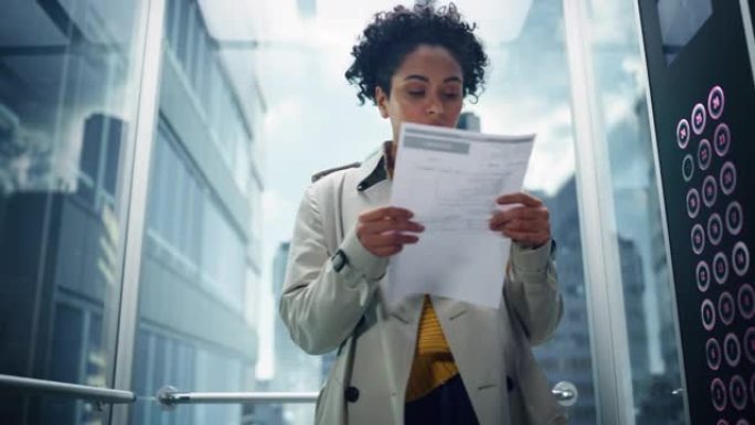 紧张的黑人女性专家骑着现代办公楼的玻璃电梯参加面试。多民族拉丁经理在上班迟到之前匆忙阅读财务报告。