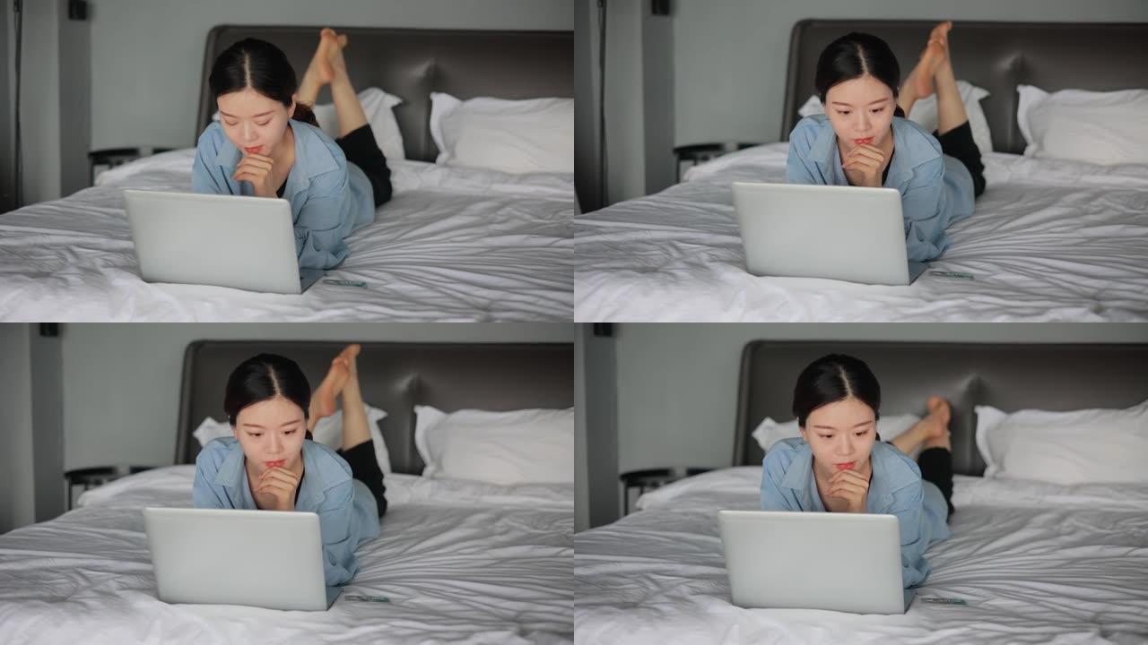 使用笔记本电脑躺在床上的年轻女性