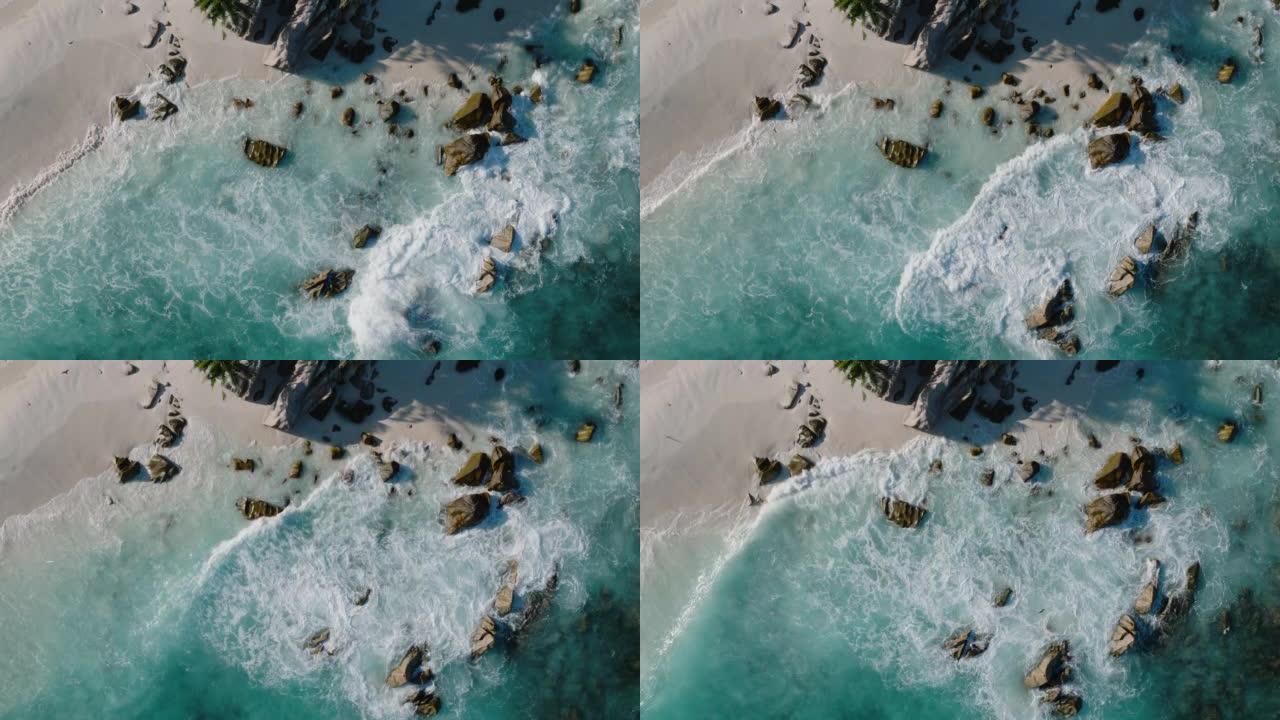 在美丽的热带岛屿海滩上，海鸟飞行和绿松石波浪在岩石上破碎的直线鸟瞰图