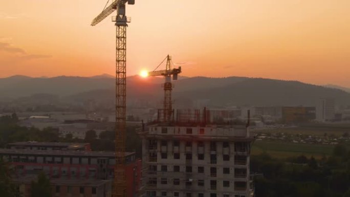 无人机: 日出时，两台起重机站在一栋正在建造的公寓楼附近