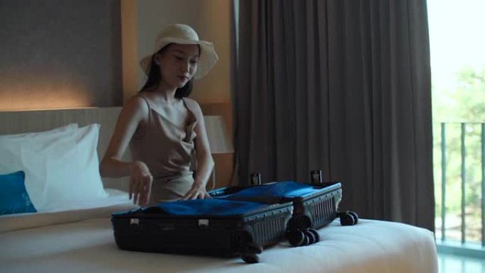 年轻的旅行女人和猫把衣服装进手提箱