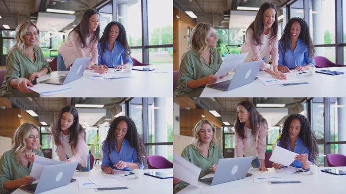 多文化女性商业团队会议坐在现代办公室的办公桌上，使用慢动作的笔记本电脑拍摄