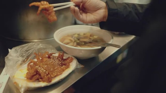 在夜市的街上享受韩国街头美食的亚洲男人。