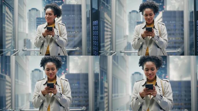 美丽的黑人女性骑玻璃电梯到现代商务中心的办公室。成功的经理在使用智能手机时微笑，写短信，查看社交媒体