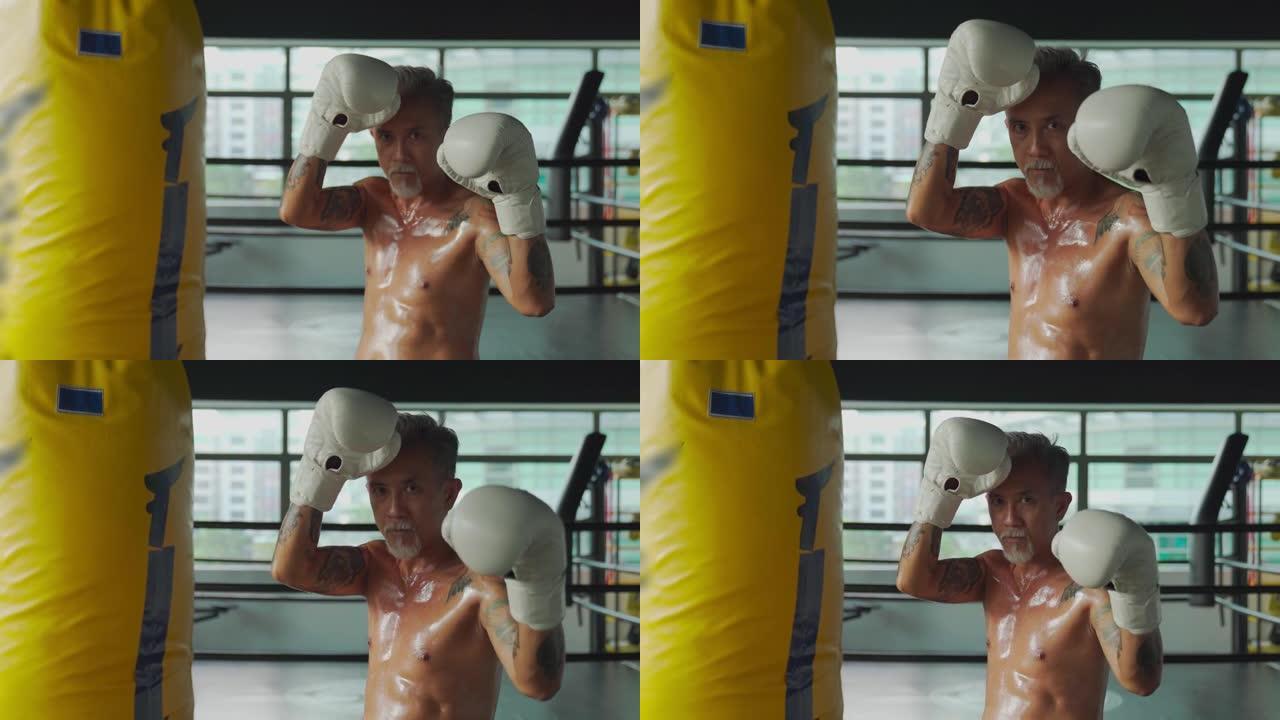 锻炼后，亚洲中国泰拳高级战士肖像在健身房的一排出气筒旁边看着相机