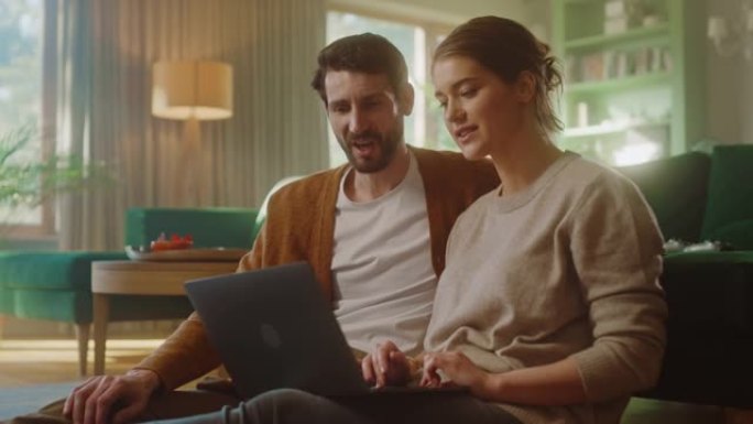夫妻俩坐在舒适的客厅里，使用笔记本电脑，庆祝高五。成功的男女朋友聊天，在网上购物，选择在线订购的产品