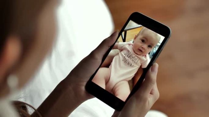 母亲在家中通过视频通话在智能手机上与婴儿交谈