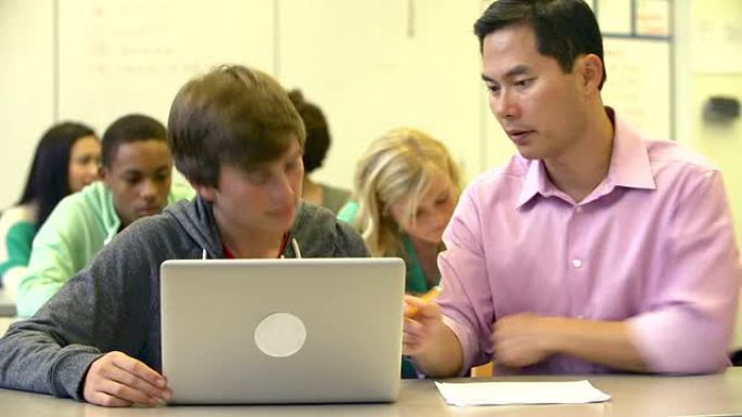 男高中生与老师一起使用笔记本电脑