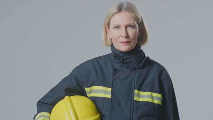 在朴素的背景下，严肃的成熟女消防员的工作室肖像