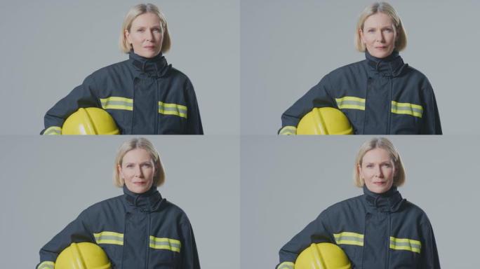 在朴素的背景下，严肃的成熟女消防员的工作室肖像