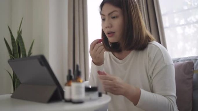 女人在家里的客厅用数字平板电脑学习化妆，独自化妆
