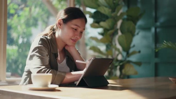 亚洲女性在咖啡馆使用数字平板电脑工作