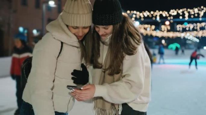 两名年轻女性在溜冰场上使用手机发短信