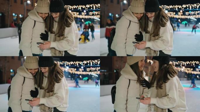 两名年轻女性在溜冰场上使用手机发短信