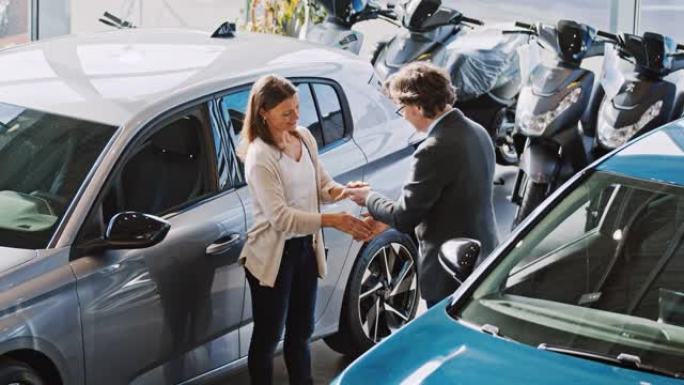 SLO MO汽车推销员握手并将新车的钥匙交给女顾客