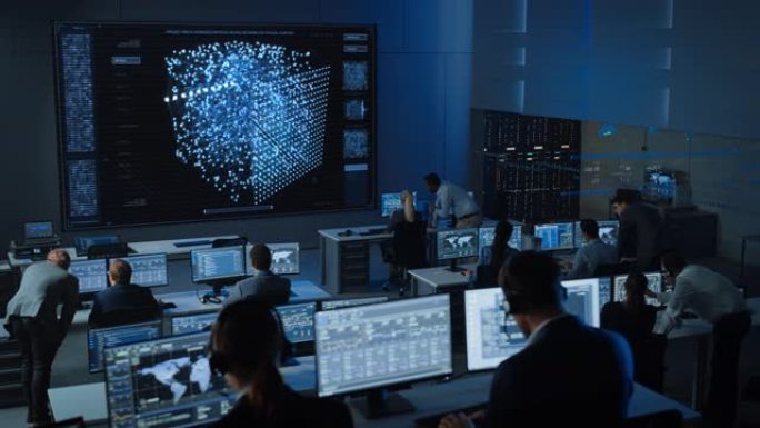 在现代监控办公室工作的工程师的移动镜头，在大屏幕上显示实时神经网络。监控室大数据科学家和管理人员坐在