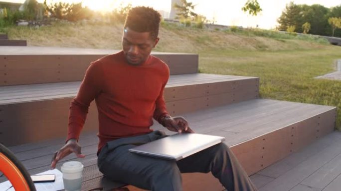 在公园里使用笔记本电脑的年轻非洲裔美国商人