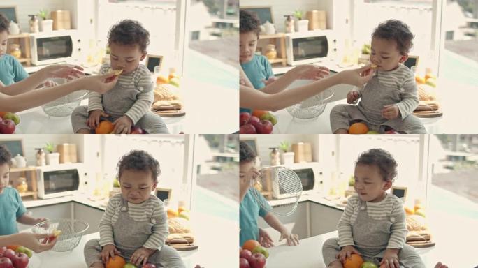 SLO MO妈妈在厨房里用橘子喂儿子