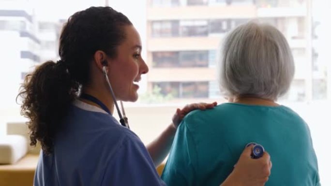 老年医学机构的女护士用一名无法辨认的高级妇女的听诊器检查肺部